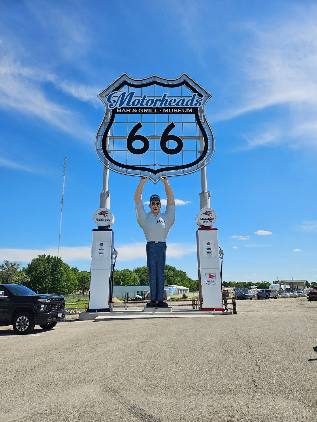 a large fiberglass man holding a sign up that says Motorheads Bar and Gtill and museum