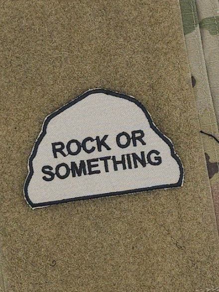Camouflage fabric with a patch reading 'Rock or Something' on a white background