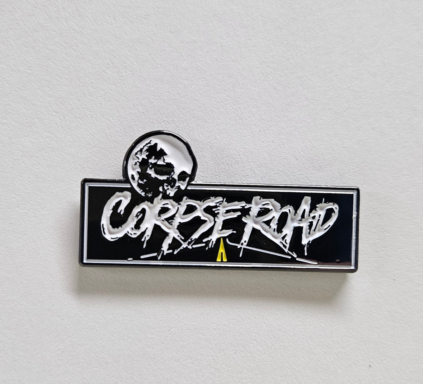 Pin with 'CORPSE ROAD' text on a white background