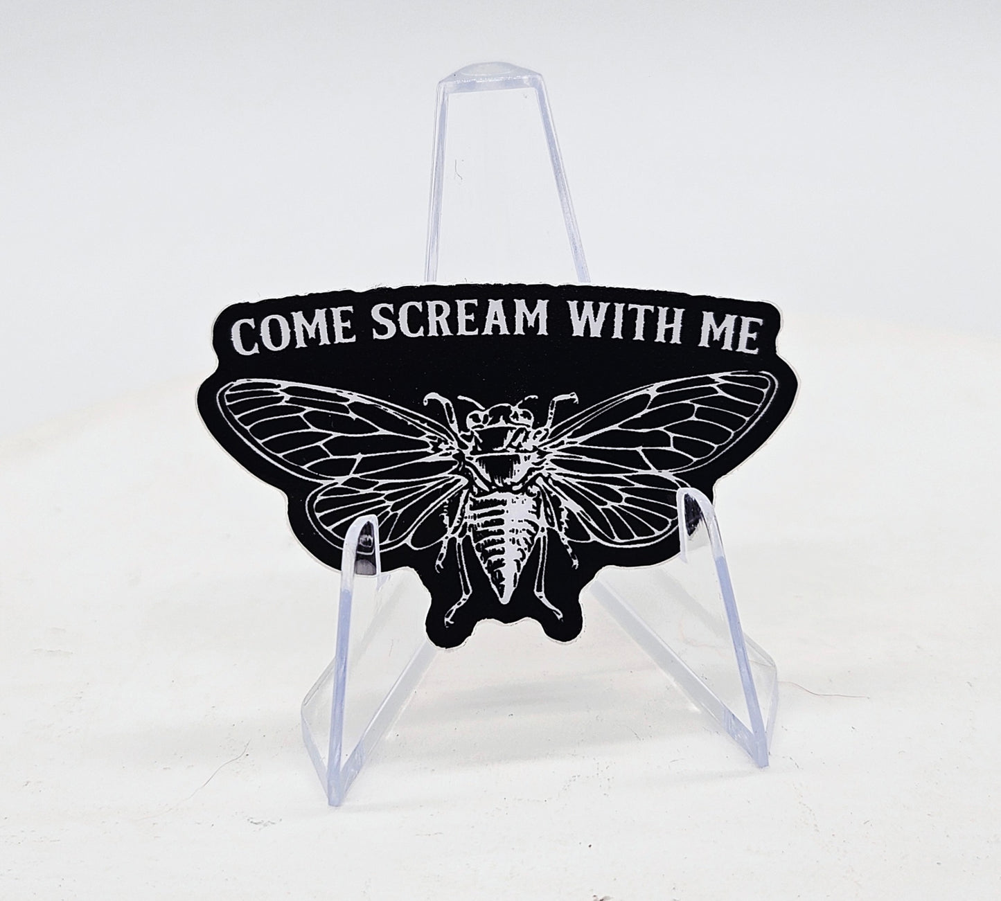 Black and white cicada design with text 'COME SCREAM WITH ME' on a stand against a white background