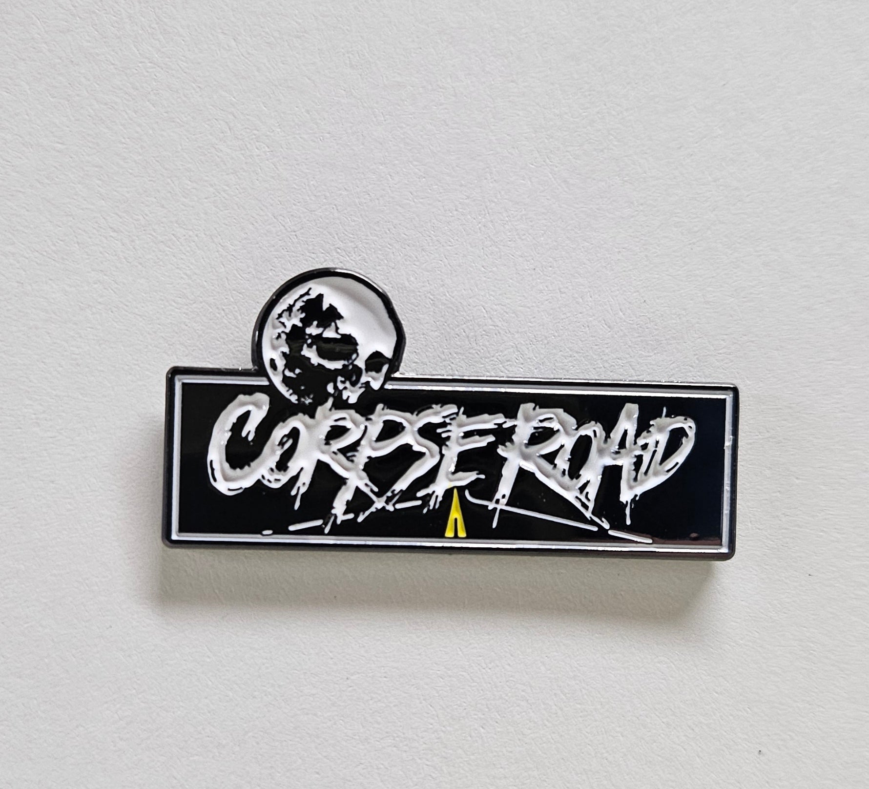 Pin with 'CORPSE ROAD' text on a white background