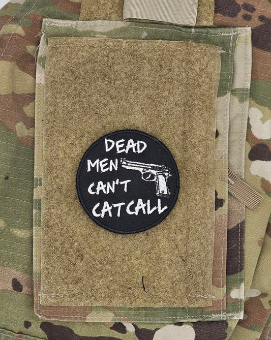 Patch with 'Dead Men Can't Catcall' text on a camouflage background. There is also a pistol